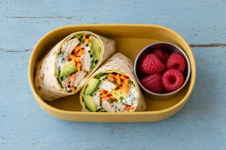 Wrap met kip, avocado en wortel, met frambozen.