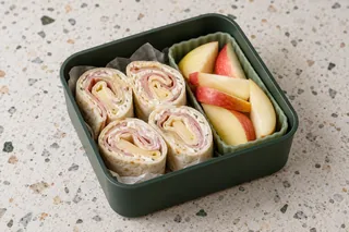 Tortillarolletjes met ham, kaas en roomkaas, met appel.