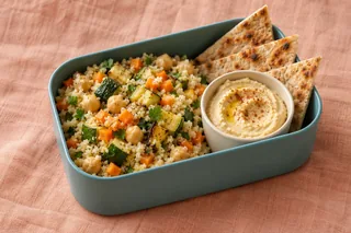 Couscous met kikkererwten, wortel en courgette, met hummus en platbrood.
