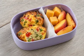 Mini-frittata met doperwten en paprika, met kaasblokjes en perzik.